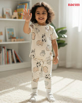 Child wearing pajamas with animal prints in a room with books and a plant.