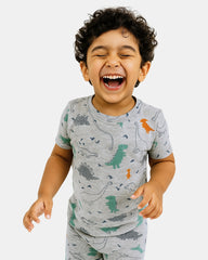Child wearing a gray pajama set with dinosaur patterns on a white background