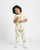 Child wearing a white pajama set with yellow giraffe prints on a white background