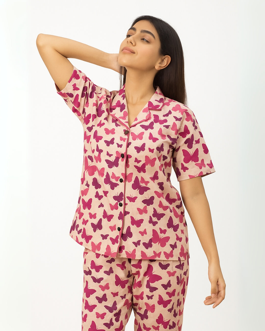Woman wearing a pink butterfly pattern pajama set on a white background