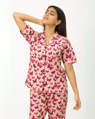 Woman wearing a pink butterfly pattern pajama set on a white background
