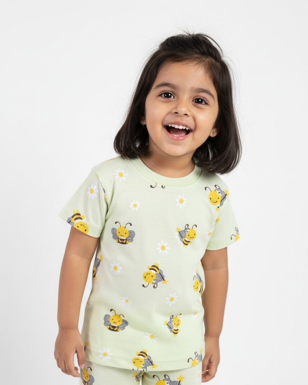 Child wearing a light green outfit pajama set with bee patterns on a white background