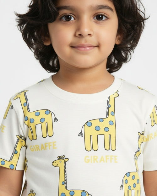 Child wearing a white t-shirt with yellow giraffe prints pajama set on a plain background