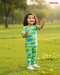 Child in a green and blue nightwear outfit standing in a grassy field with a butterfly.