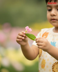 Kids in night wear holding a pink flower and green leaf with a blurred natural background