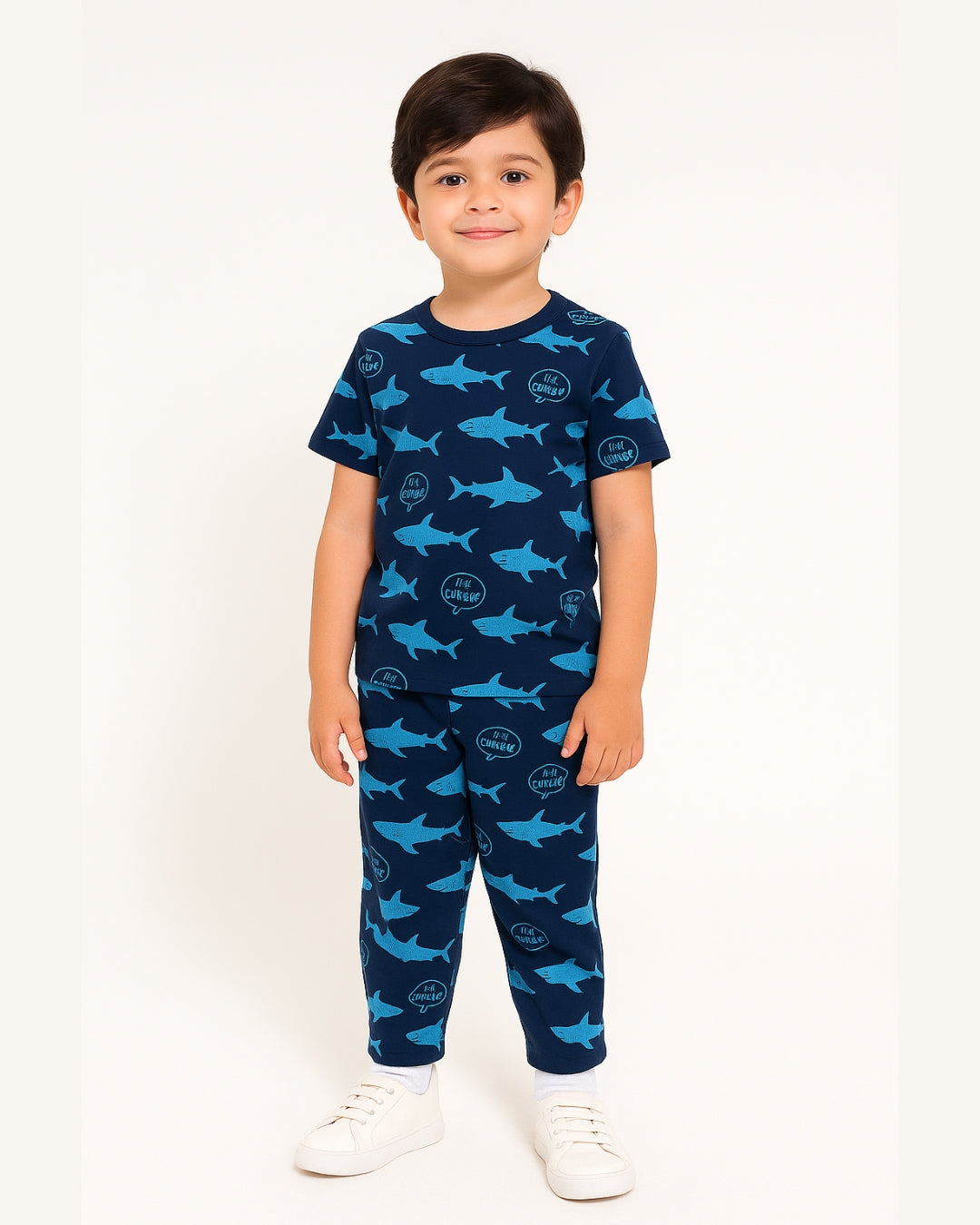 Child wearing a navy blue pajama set with shark pattern on a white background