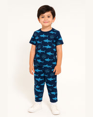 Child wearing a navy blue pajama set with shark pattern on a white background