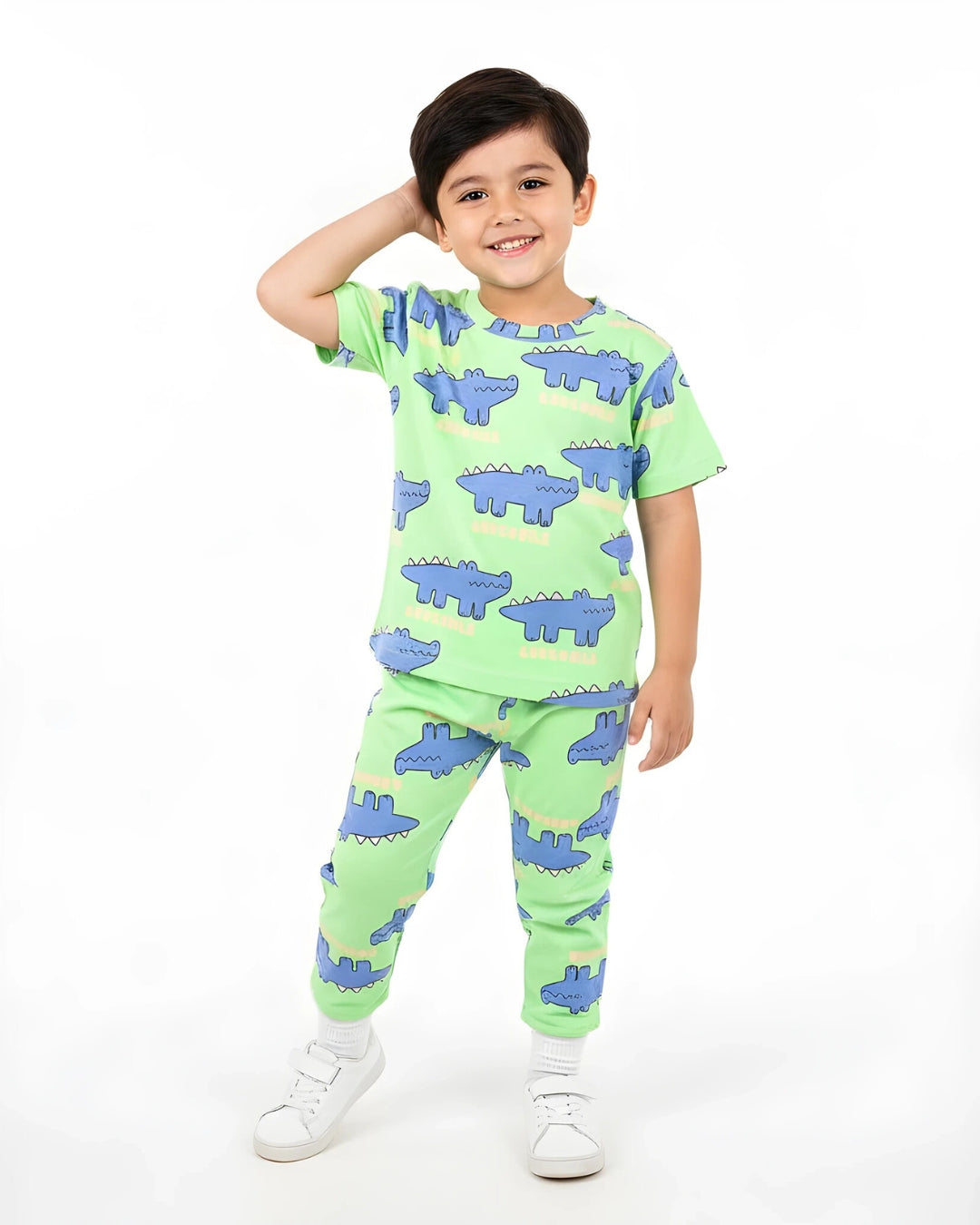 Child wearing a green pajama set with blue crocodile patterns on a white background