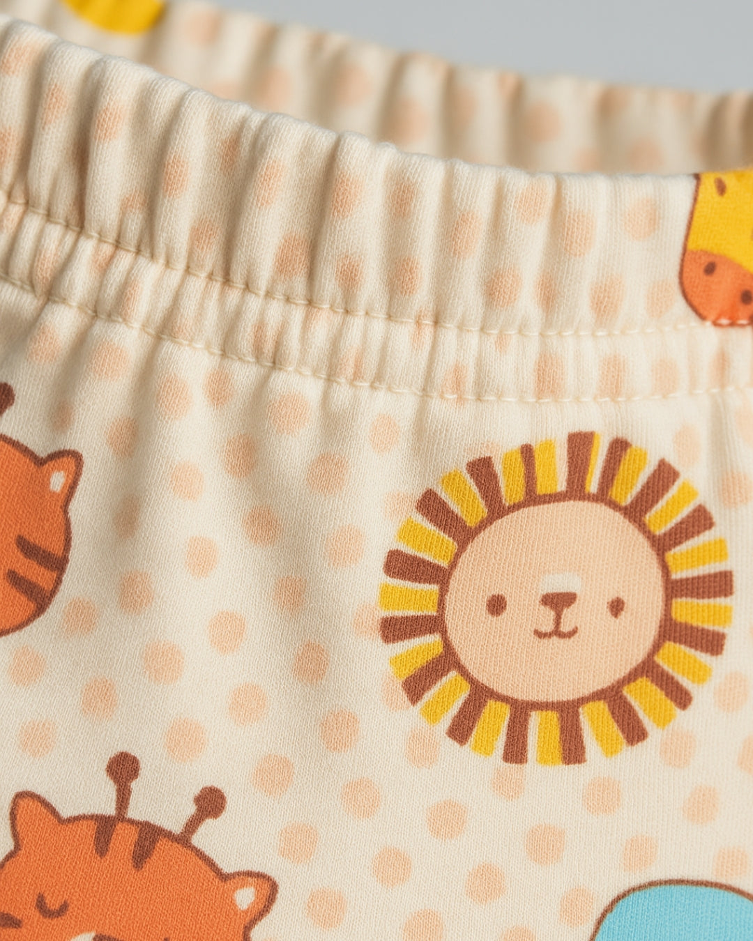 Close-up of children's shorts with lion and tiger designs on a beige background