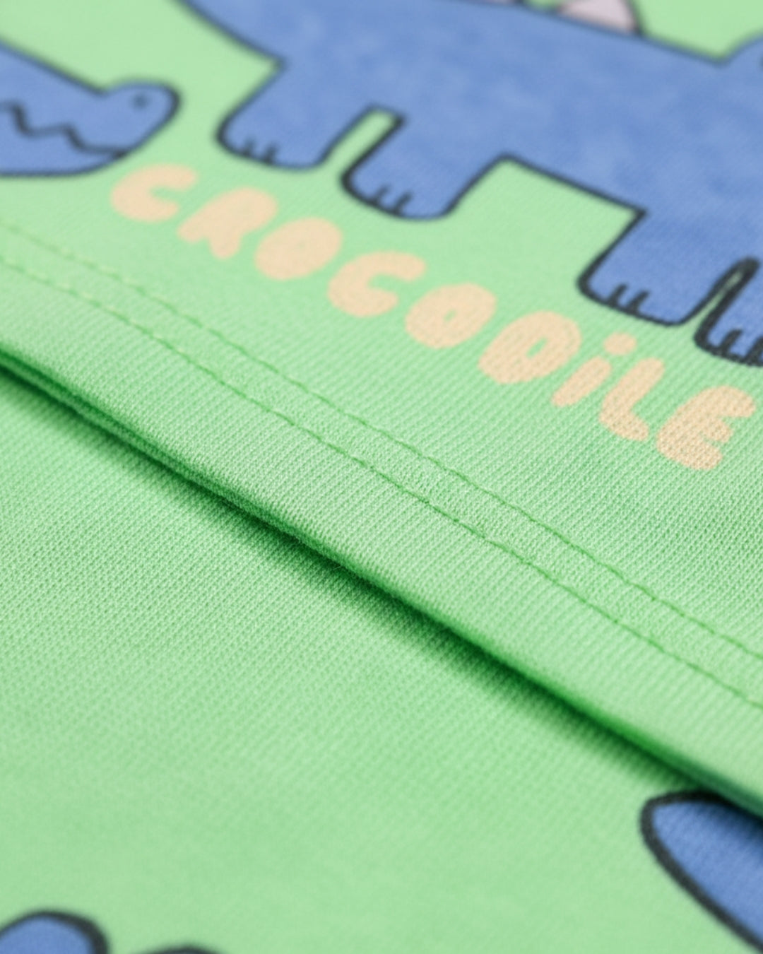 Close-up of green fabric with blue crocodile shapes and 'CROCODILE' text.
