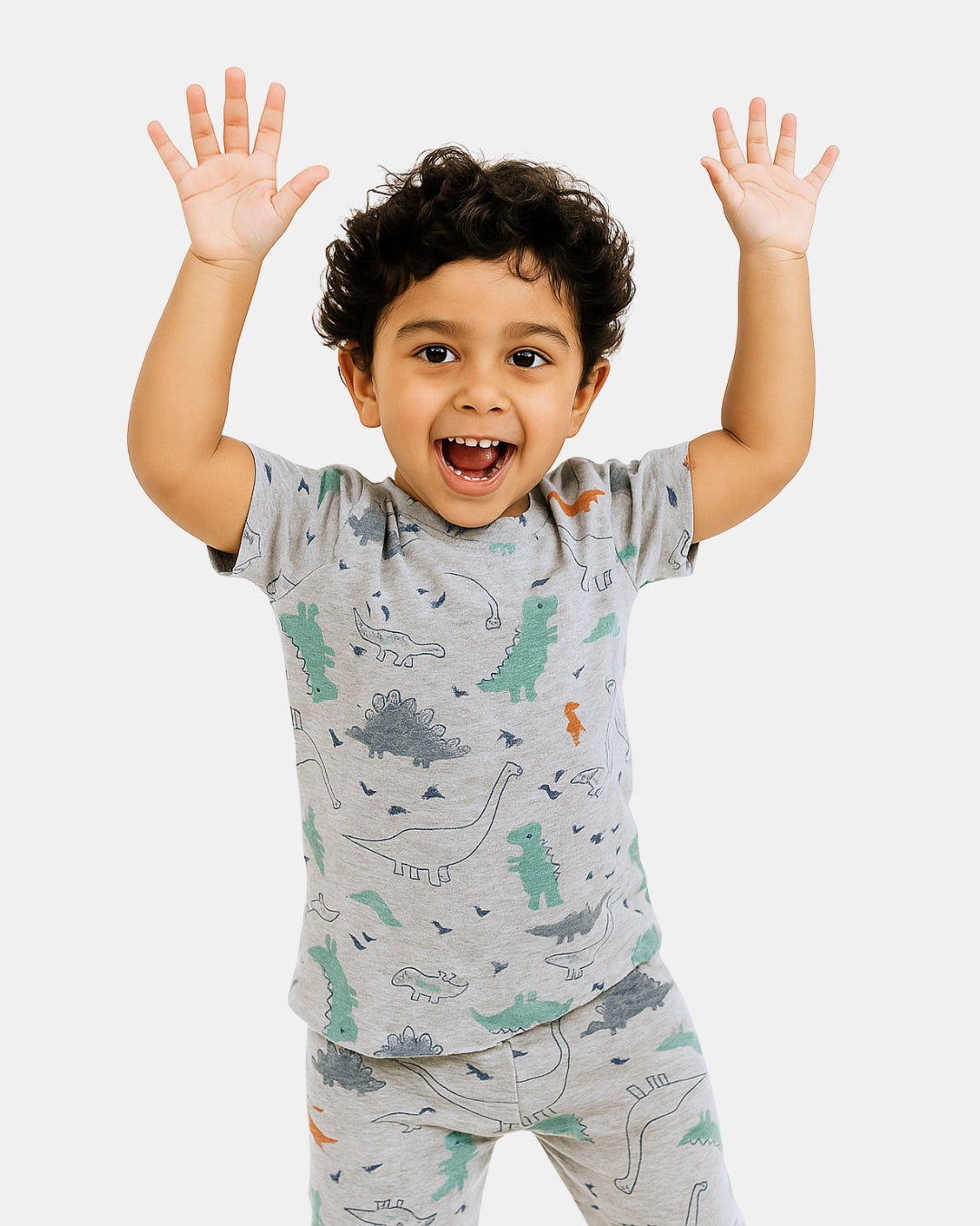 Child wearing a gray dinosaur-patterned pajama set with arms raised on a white background