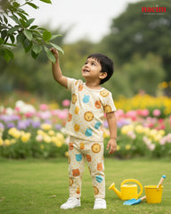 Kids in a pajama set on a garden with flowers and toys, wearing a colorful outfit.