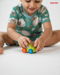 Child playing with a colorful toy car on a white surface