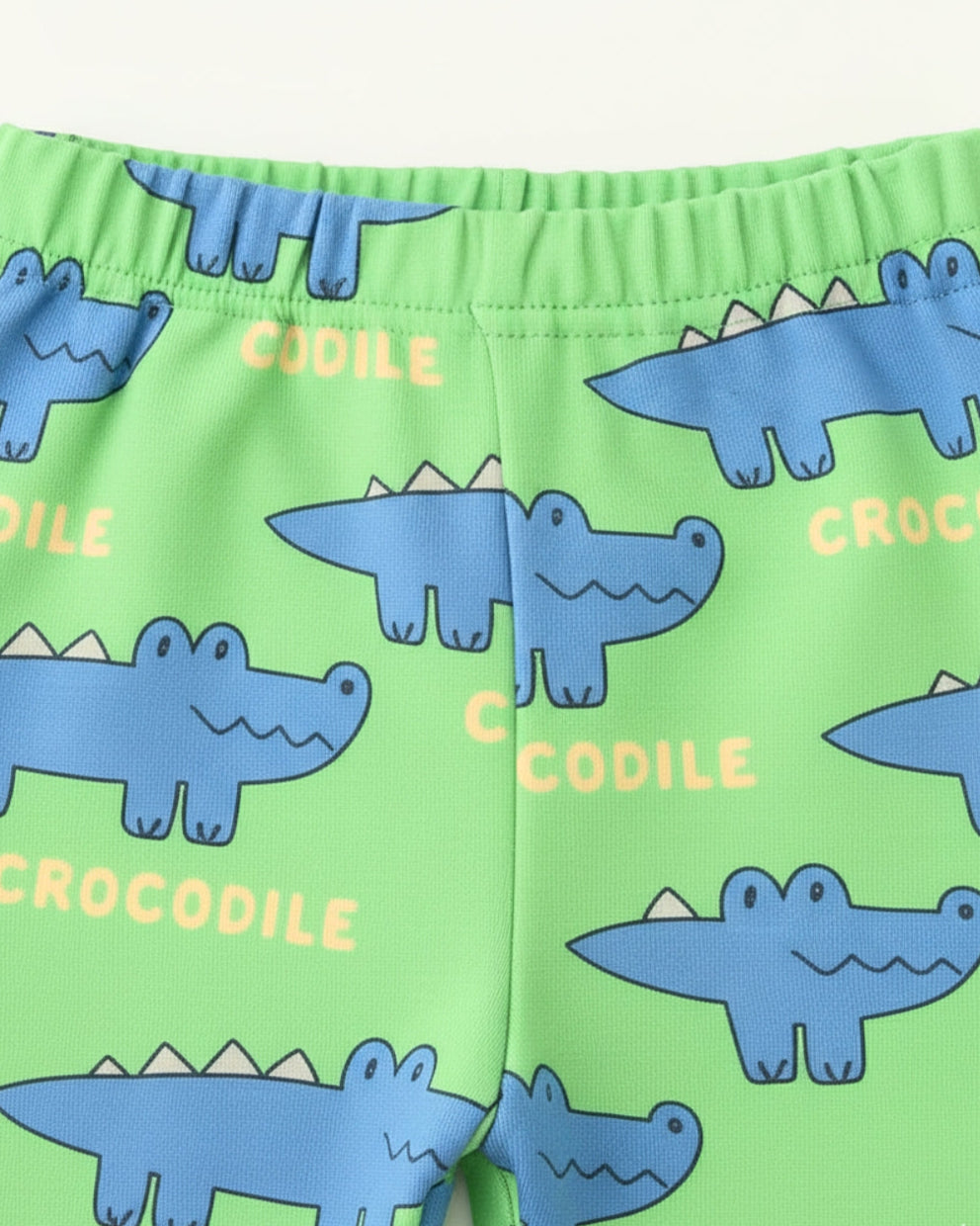 Green shorts with blue crocodile pattern and text on a white background
