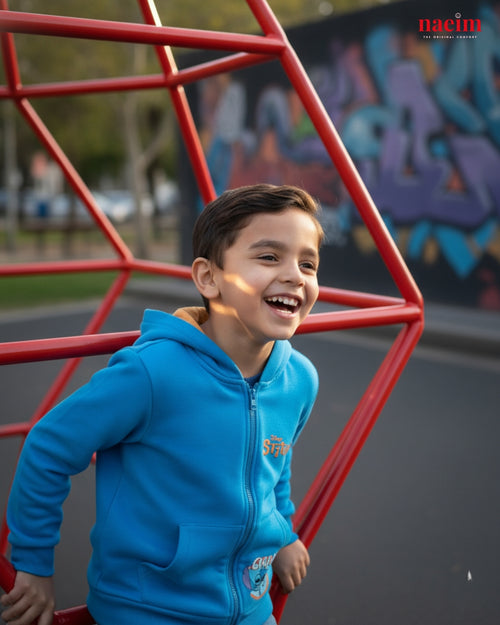 Child in a blue jacket standing in front of a red playground structure with graffiti in the background.