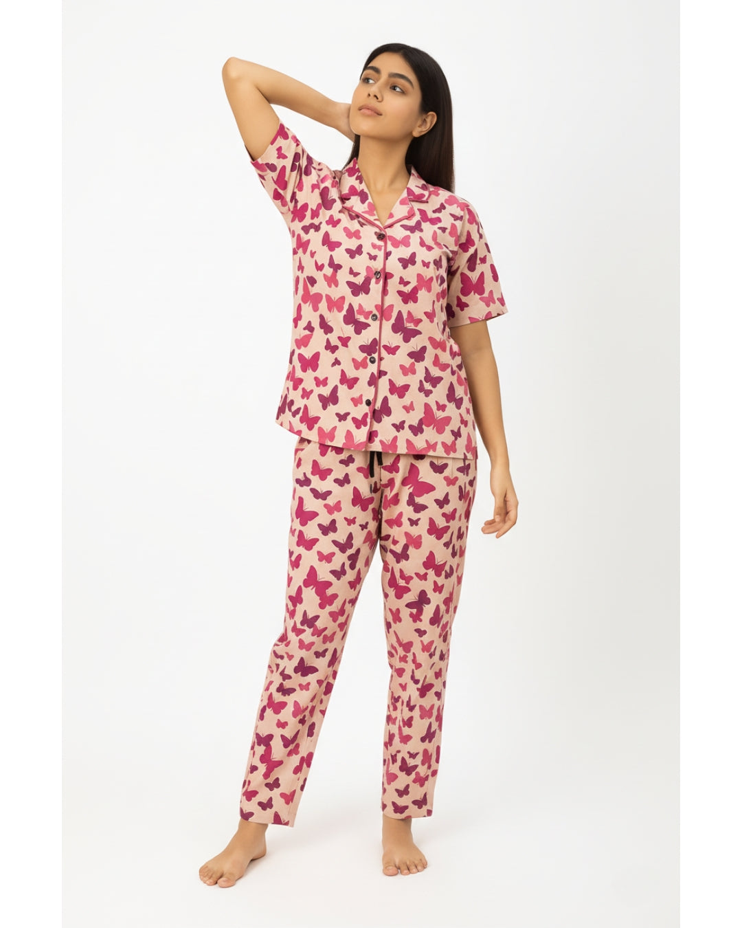 Woman wearing a pink butterfly pattern pajama set on a white background