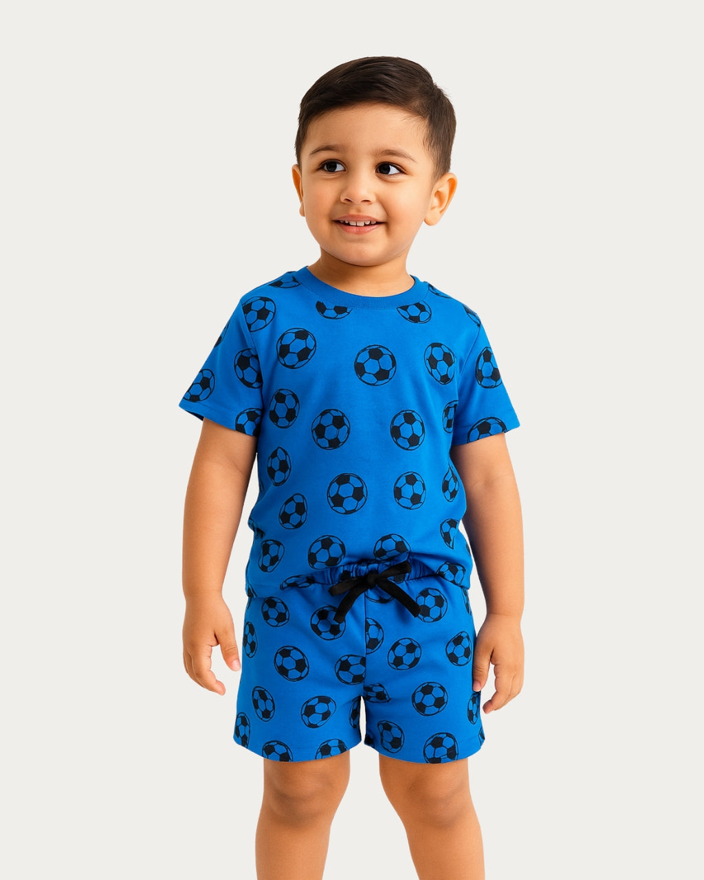 Child wearing a blue pajama set with soccer ball pattern on a white background