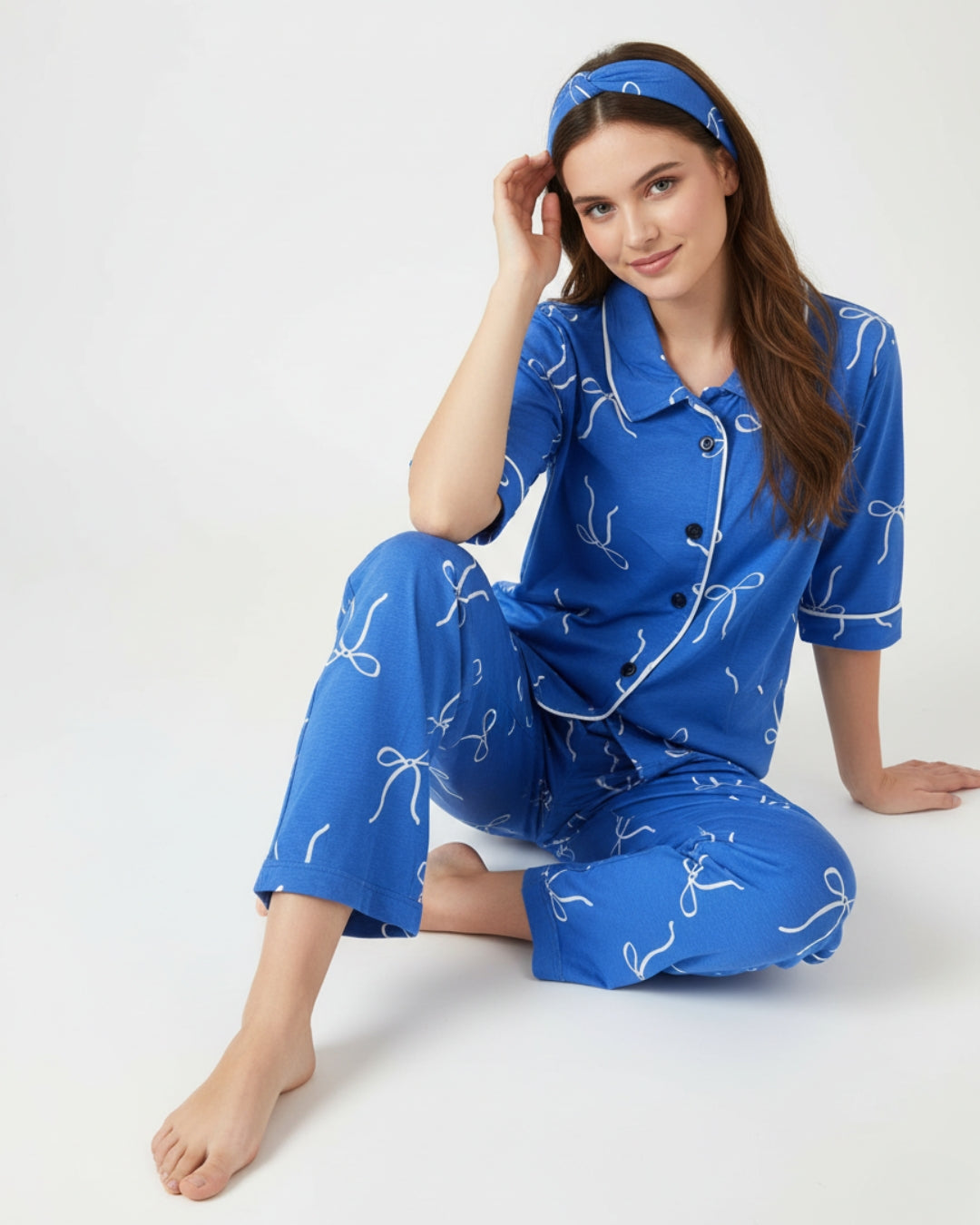 Woman wearing a blue pajama set with white patterns on a white background