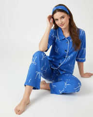 Woman wearing a blue pajama set with white patterns on a white background