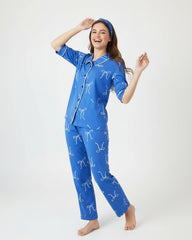 Woman wearing a blue pajama set with white bow pattern on a white background