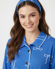 Woman wearing a blue pajama top with white accents and a matching headband on a white background