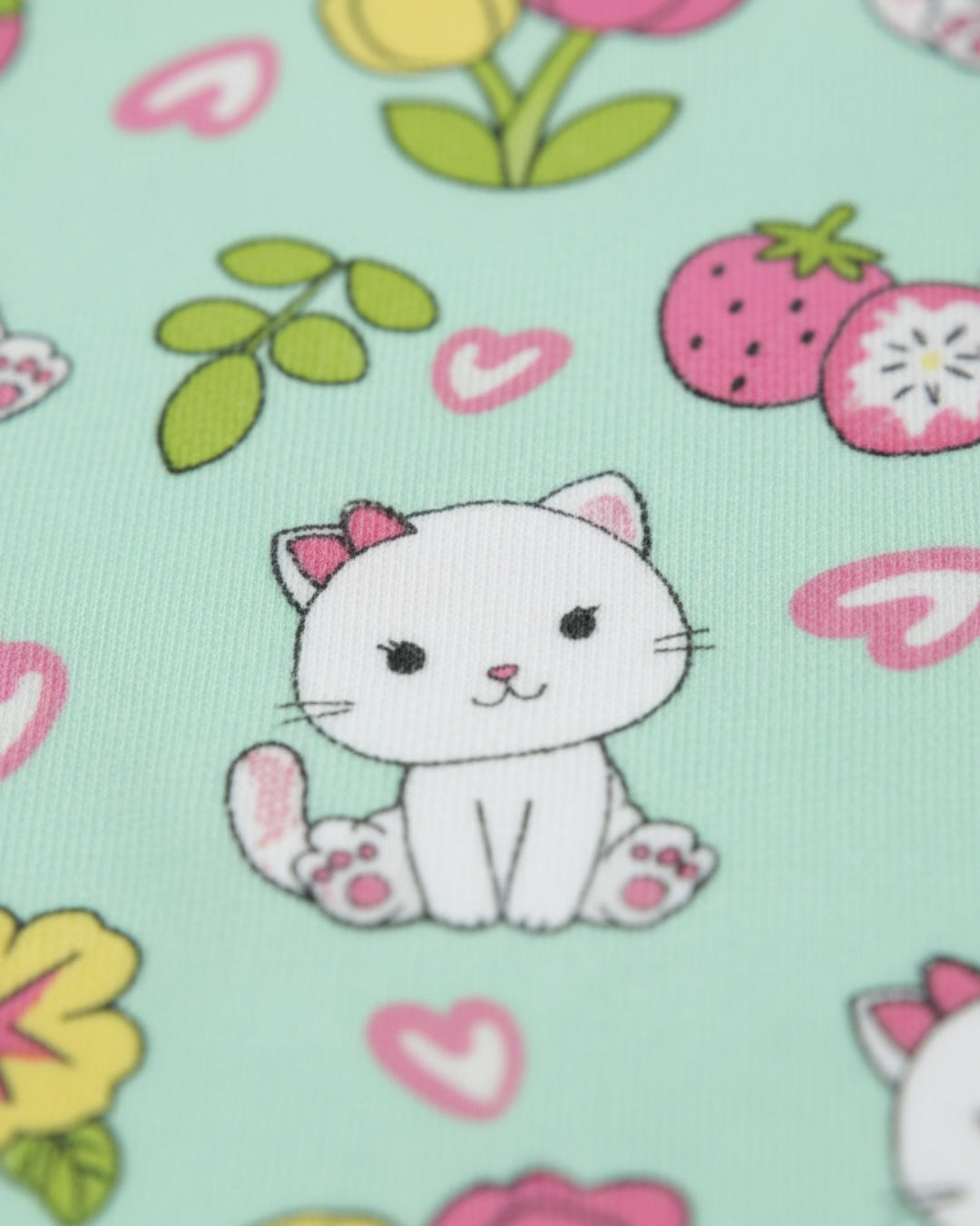 Fabric with a cartoon cat, flowers, and hearts on a light green background